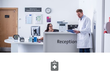 A kórházban női recepciós beszél egy fehér köpenyes orvossal; és  szürke ikon